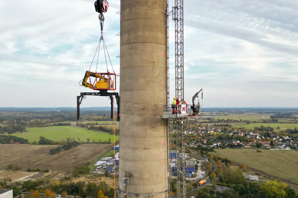 Rückbau einer Schornsteinanlage in Premnitz: Transport und Installation unsers Spinnenbaggers auf Schornsteinmündung